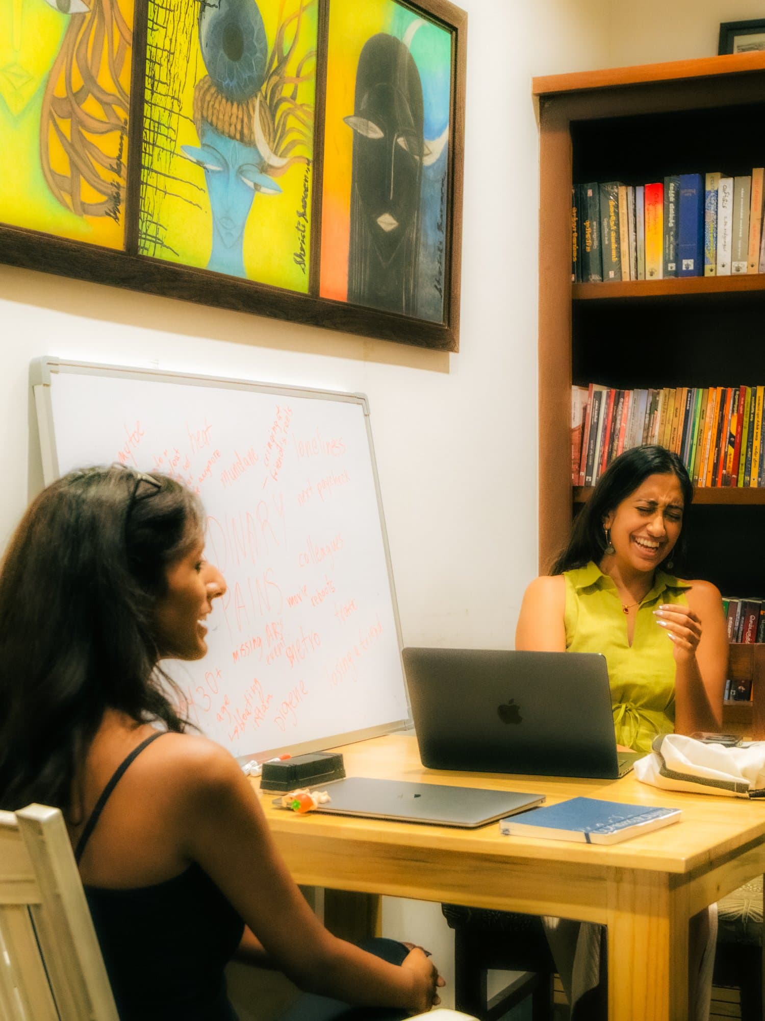 Priya Parikh laughing with a participant while hosting Writers' Evening in a library-like room.