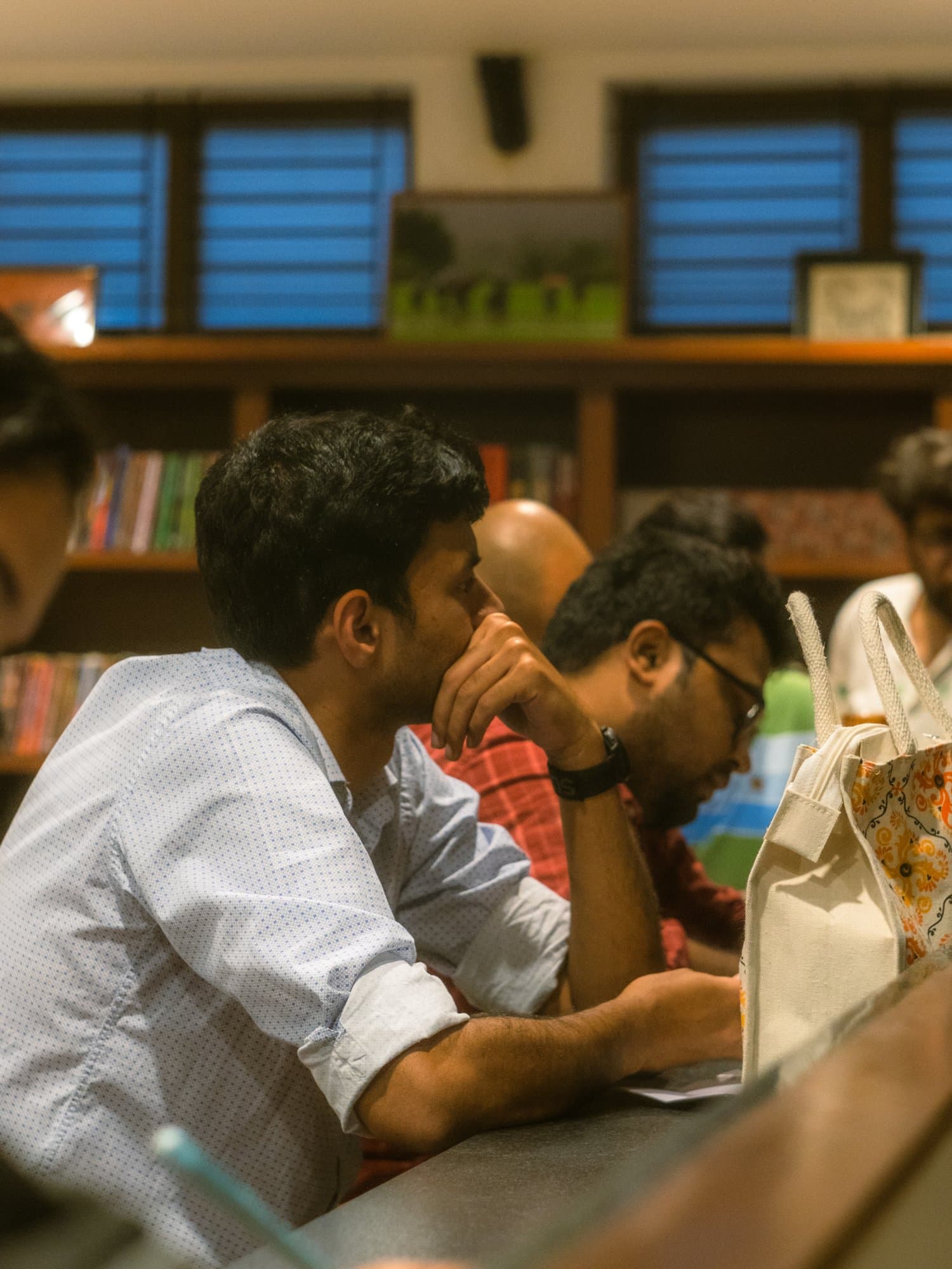 A Writers' Evening participant concentrating at a table in front of a wall of books.