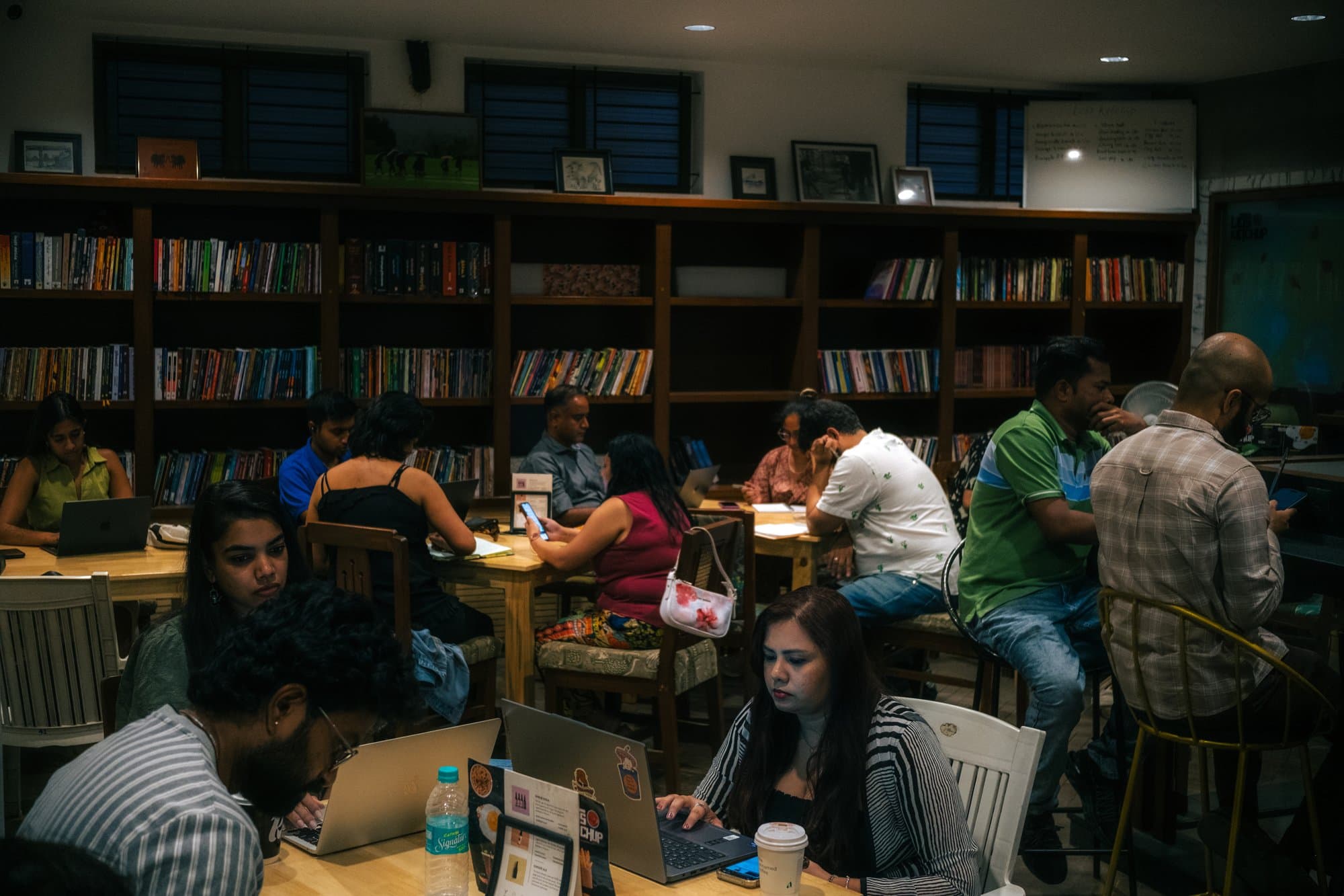 Writers' Evening participants working silently on laptops and notebooks around several tables.