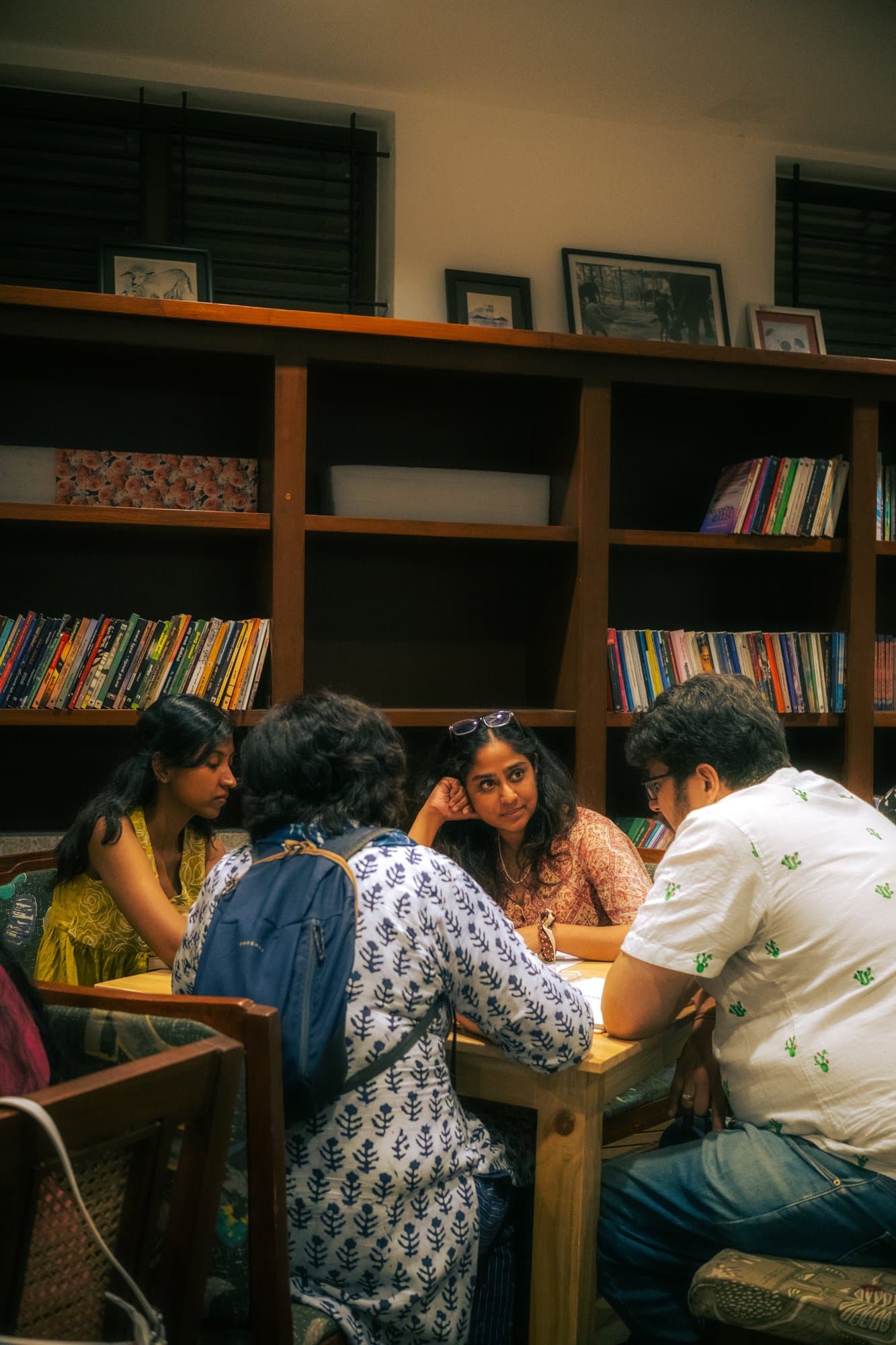 A small group of Writers' Evening participants speaking together around a wooden table.